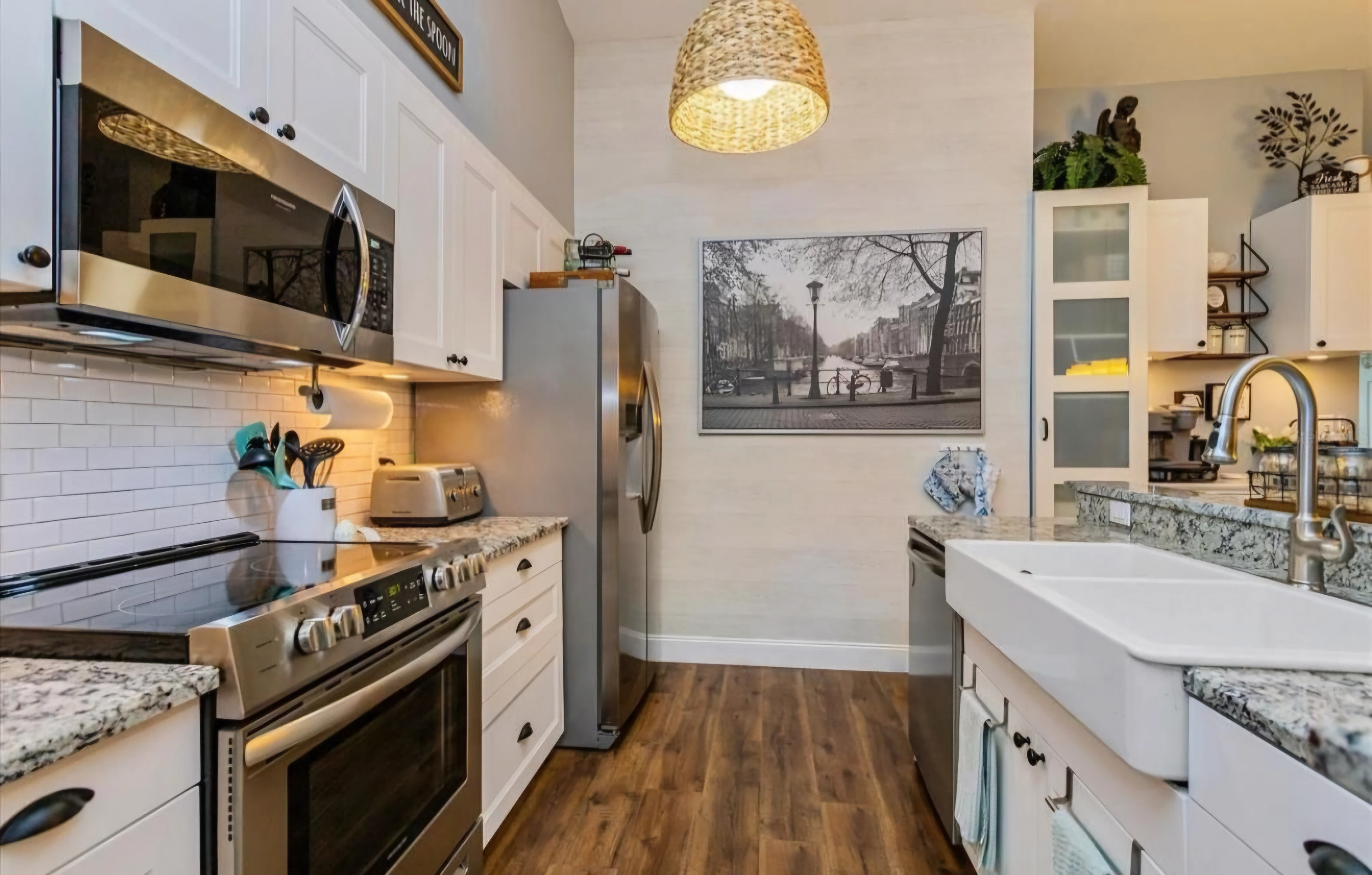 Updated kitchen with white cabinets, farmhouse sink, and woven pendant light