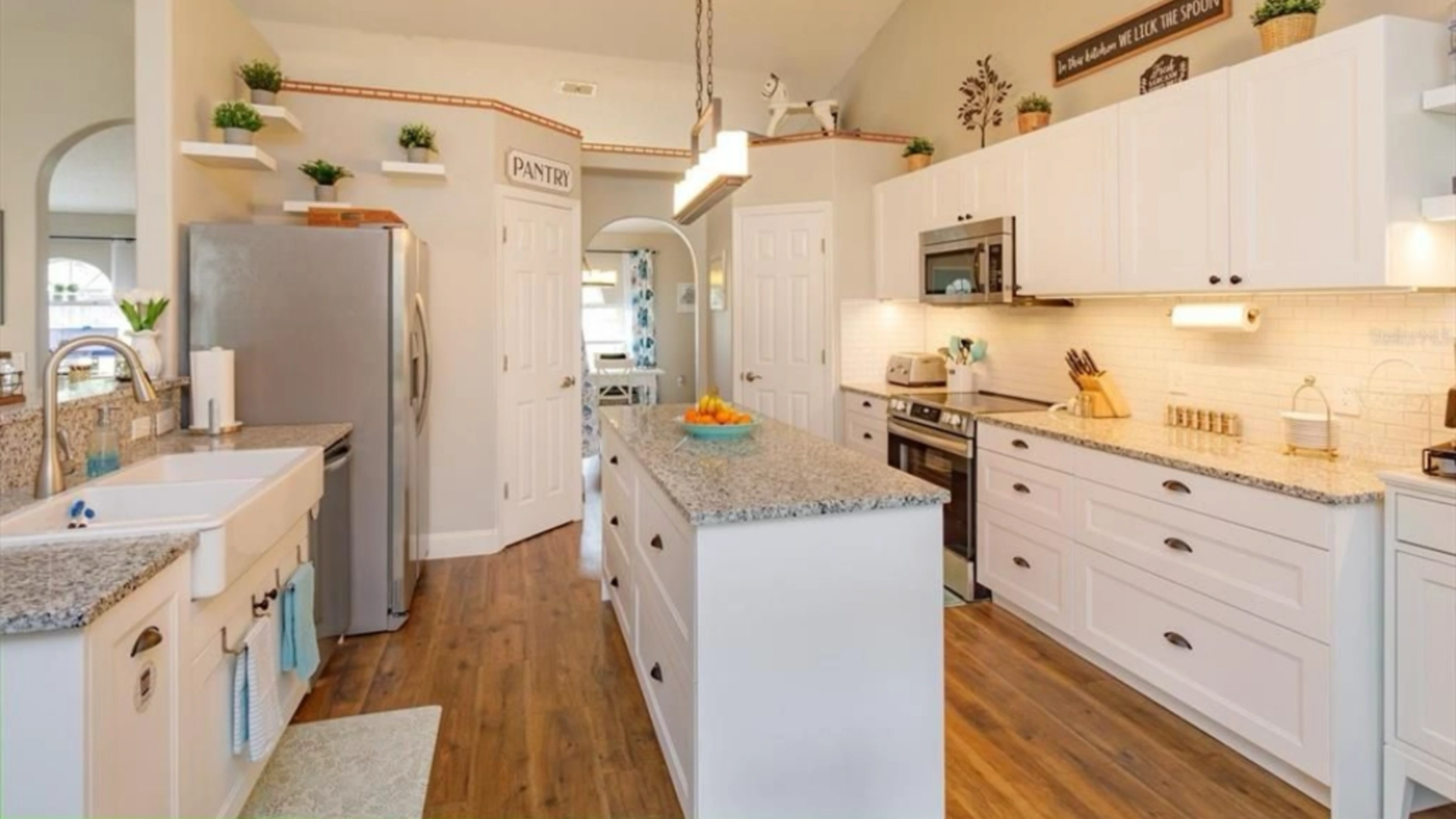 Kitchen styled with white cabinets and warm wood floors